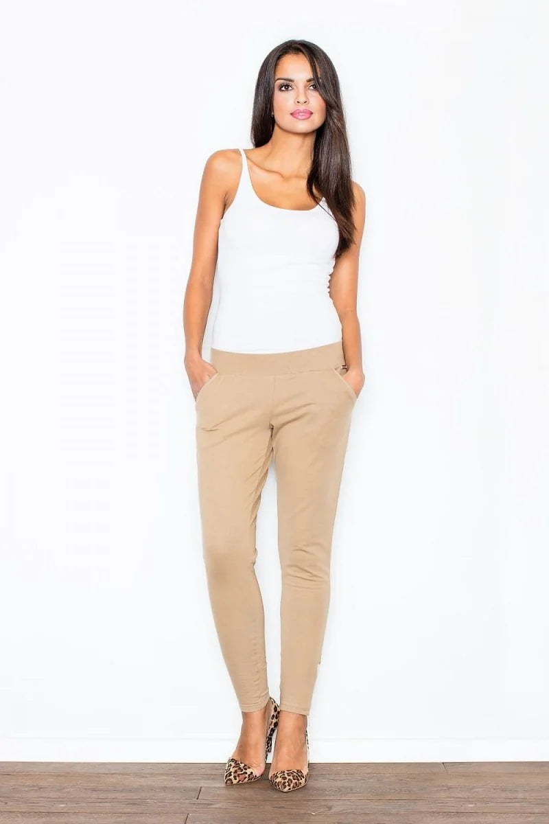 Woman in tan jogger pants and white tank top wearing leopard print heels.