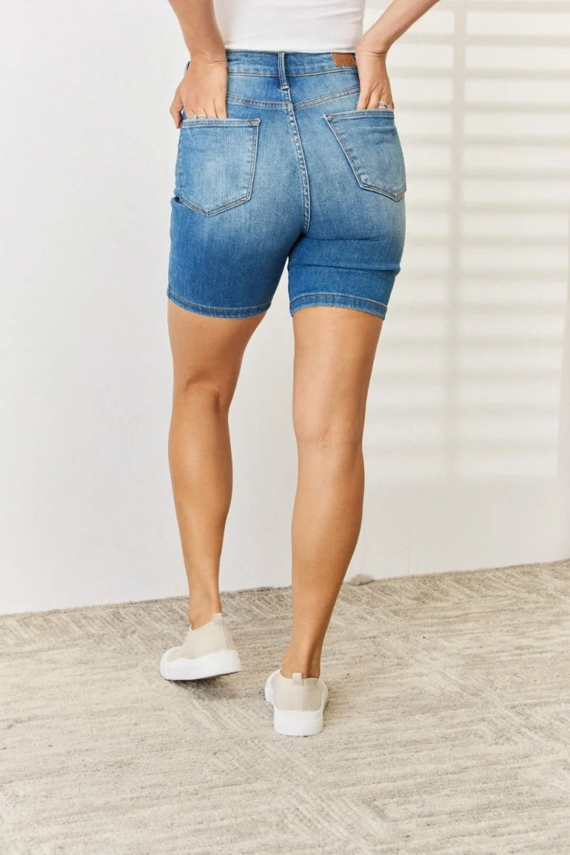 Back view of medium wash denim shorts with a fitted silhouette and visible stitching details.