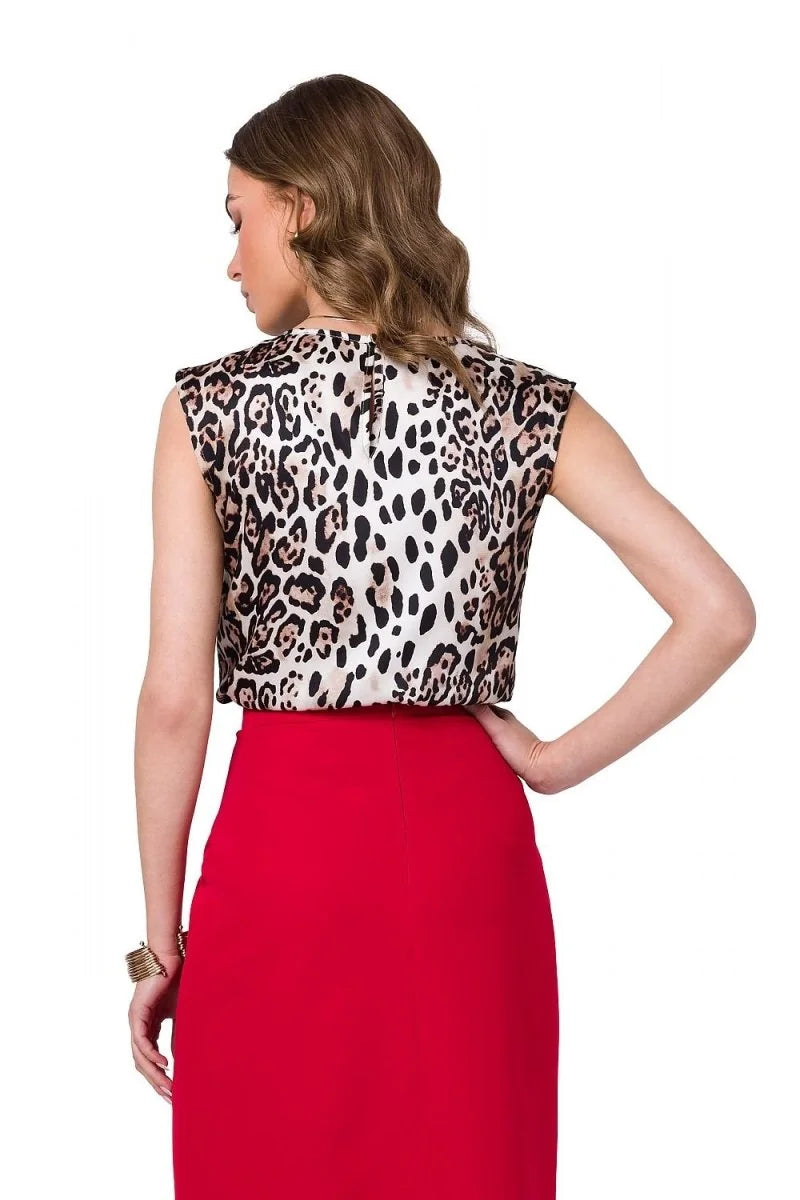 Woman from the back wearing a sleeveless leopard print top and a red skirt.