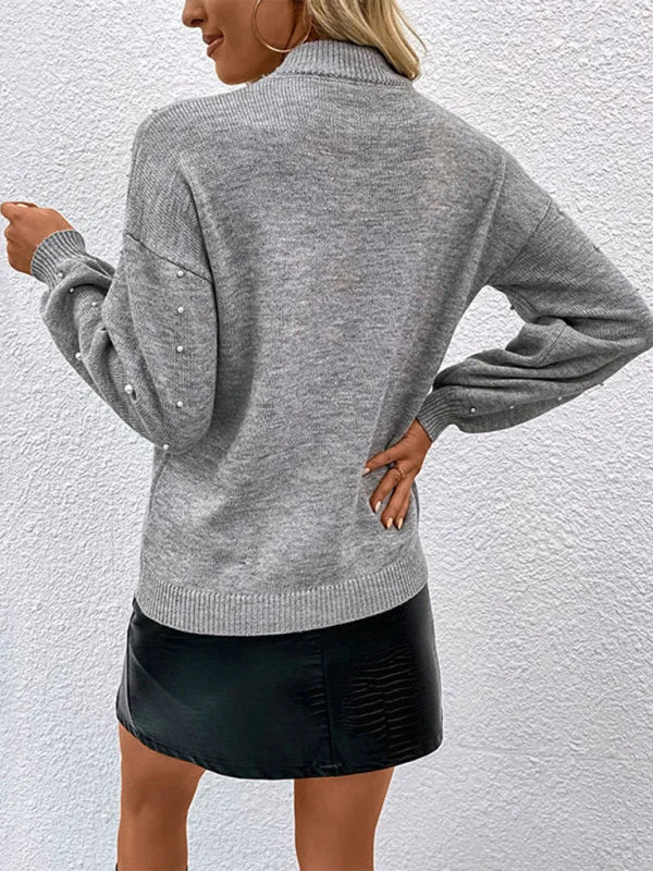 Grey relaxed fit acrylic sweater with pearl embellishments on sleeves and back, paired with a black faux leather skirt.