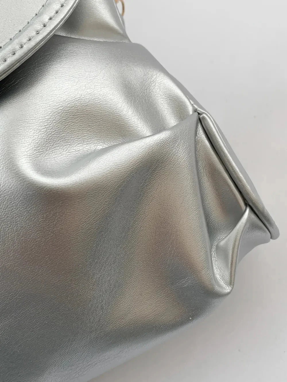 Close-up of a shiny silver handbag with soft, gathered pleats and a subtle textured finish.