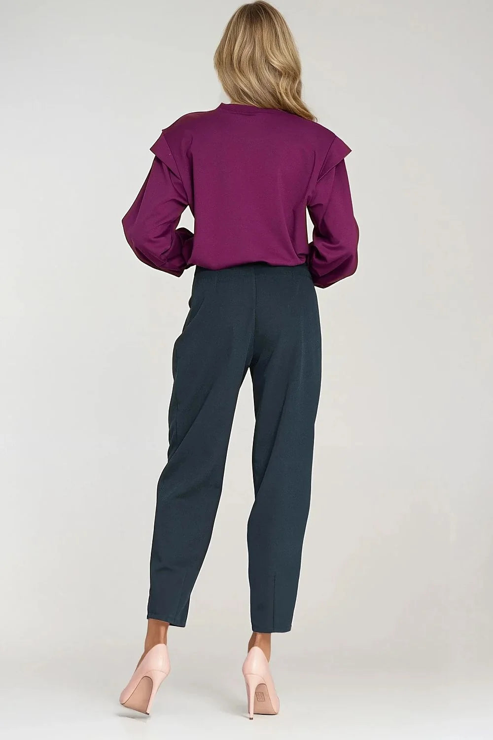 Woman from behind wearing a plum long-sleeve top with ruffled shoulders and dark teal tapered trousers.