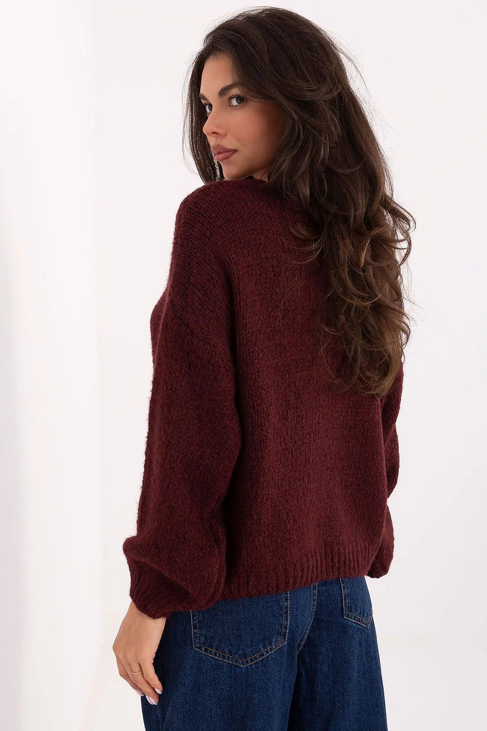 Maroon knit sweater with puffy sleeves and dark wash denim jeans, back view.