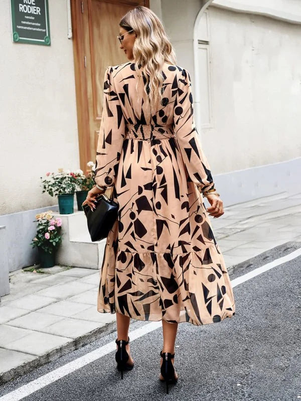Beige midi dress with abstract black print, long sleeves, and ruffled hem.