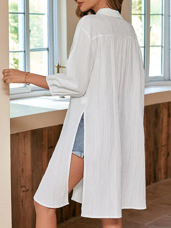 White textured tunic with side slits, worn over denim shorts.
