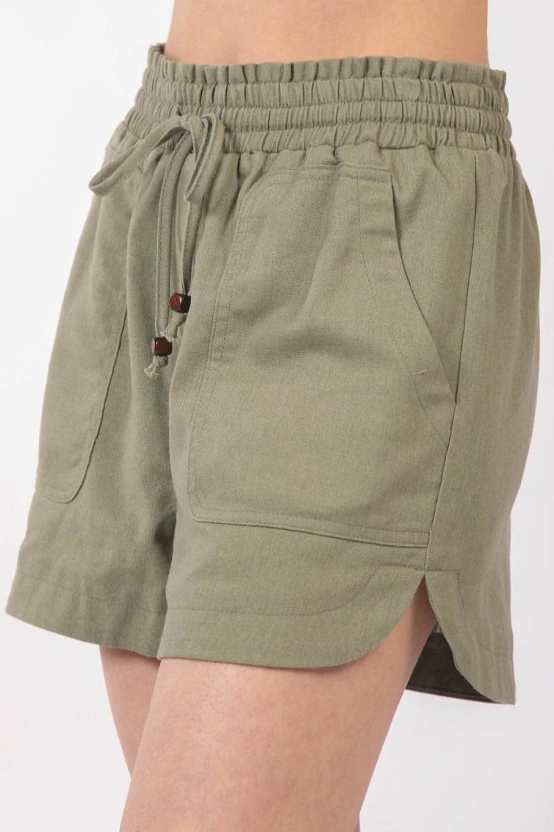 Olive green linen-blend shorts with drawstring waist and side pockets, close-up.