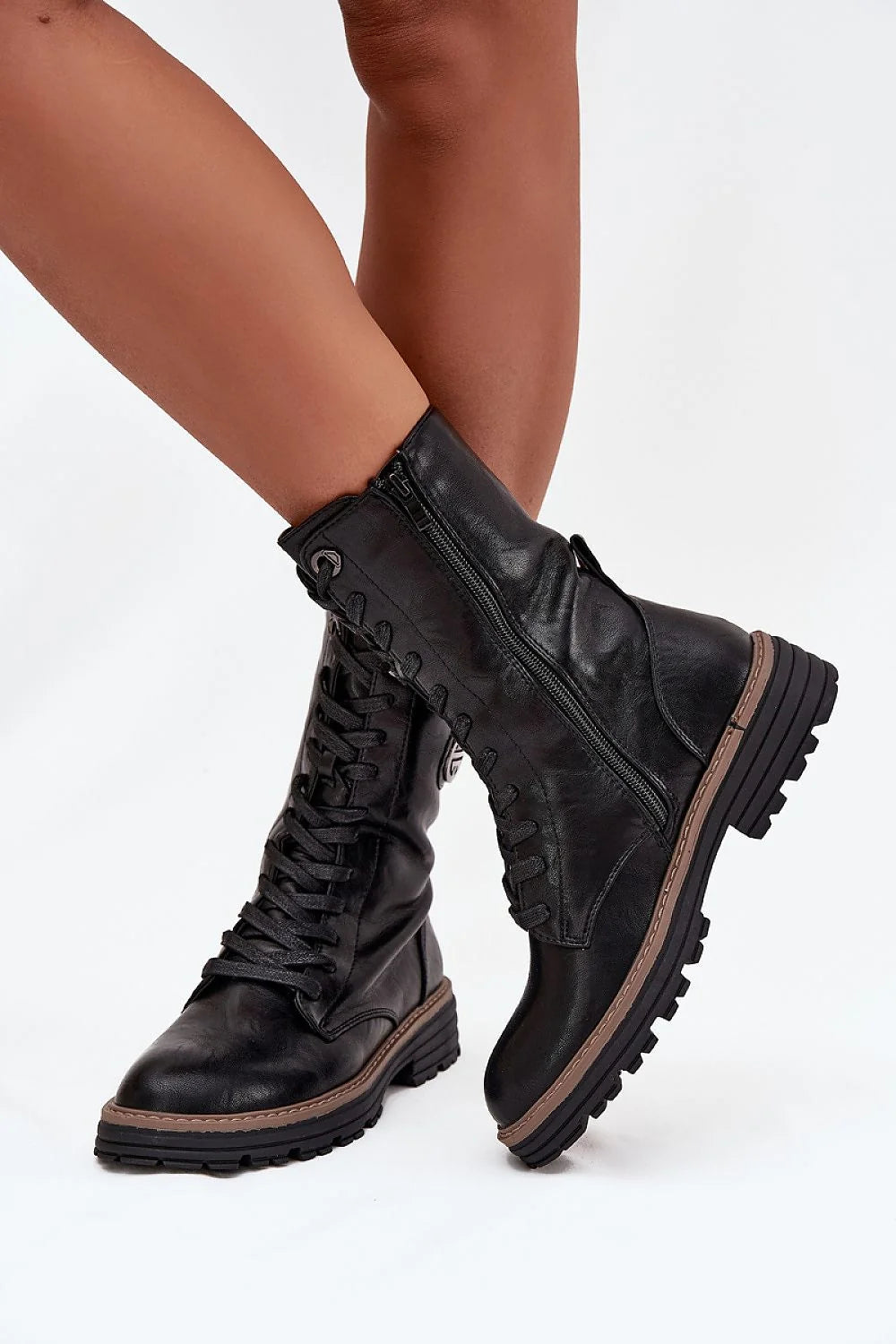 Black leather combat boots with laces and side zippers on a model's legs.