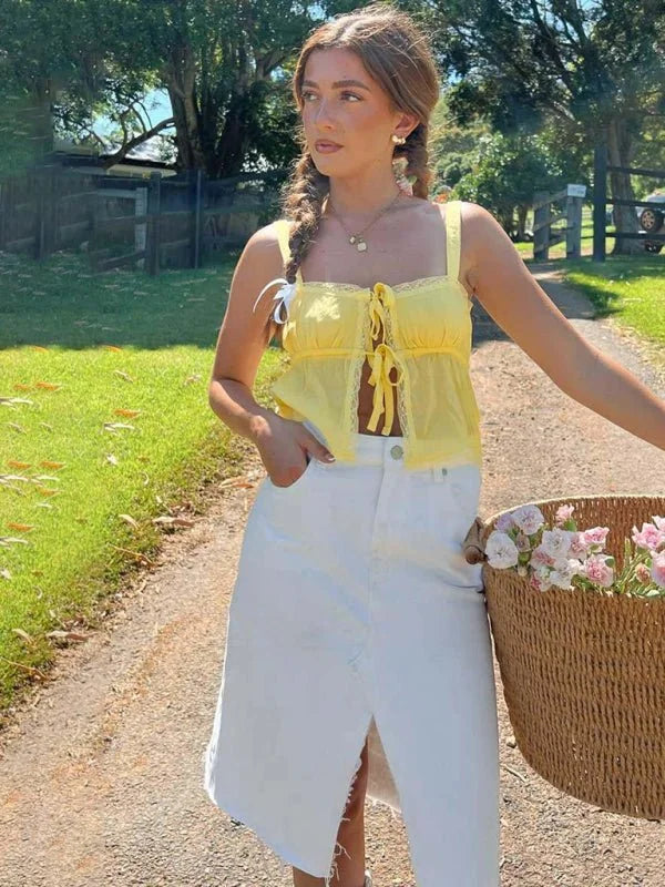 Yellow lace-trimmed tie-front crop top with white denim midi skirt on a model outdoors.
