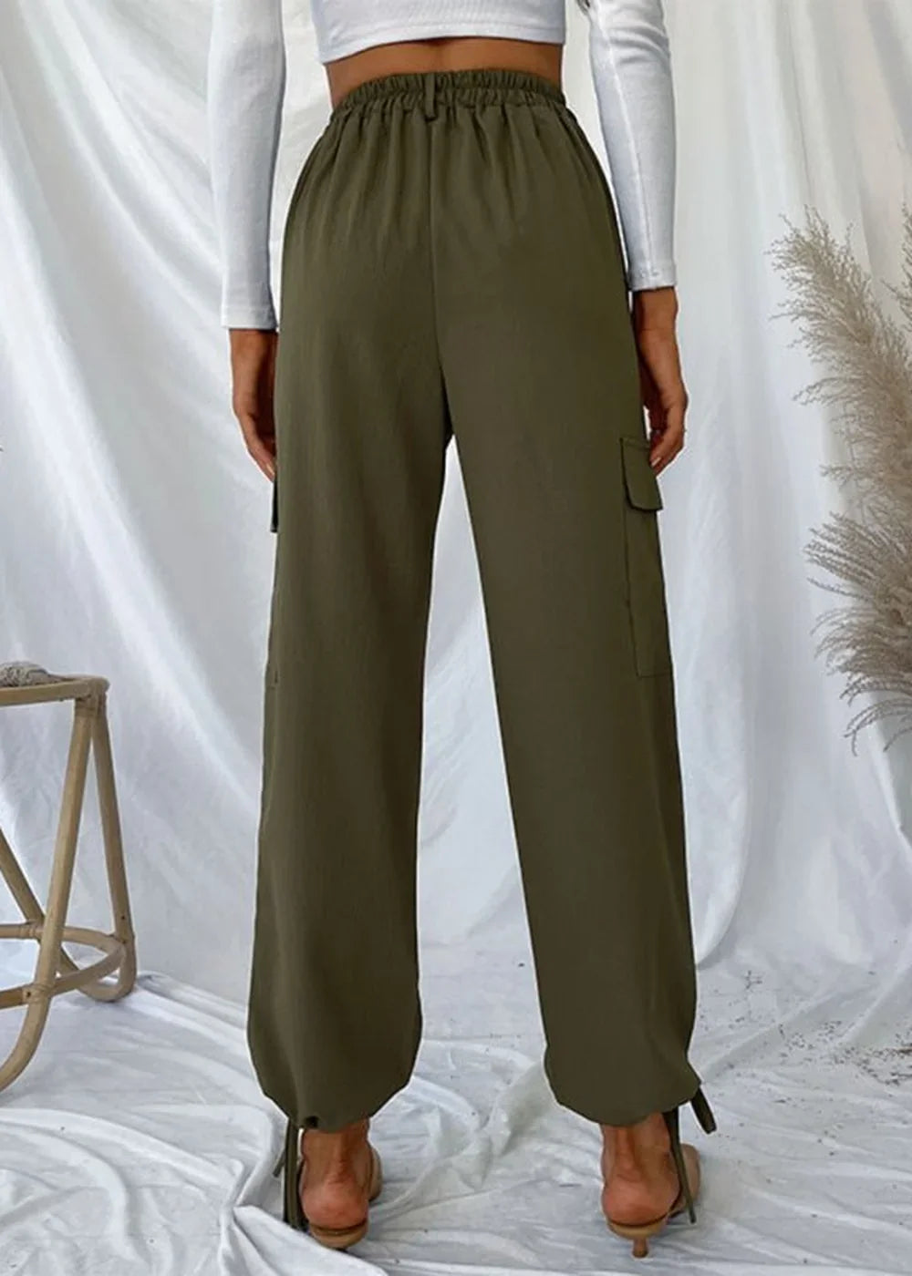 Olive green cargo pants with a drawstring waist and cuffed ankles, shown from the back.
