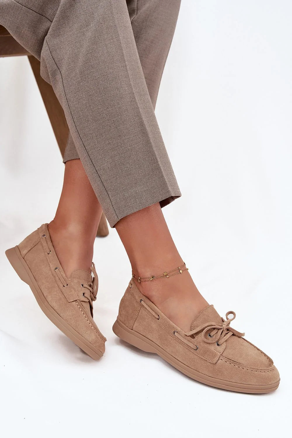 Beige suede boat shoes with laces and a star anklet.
