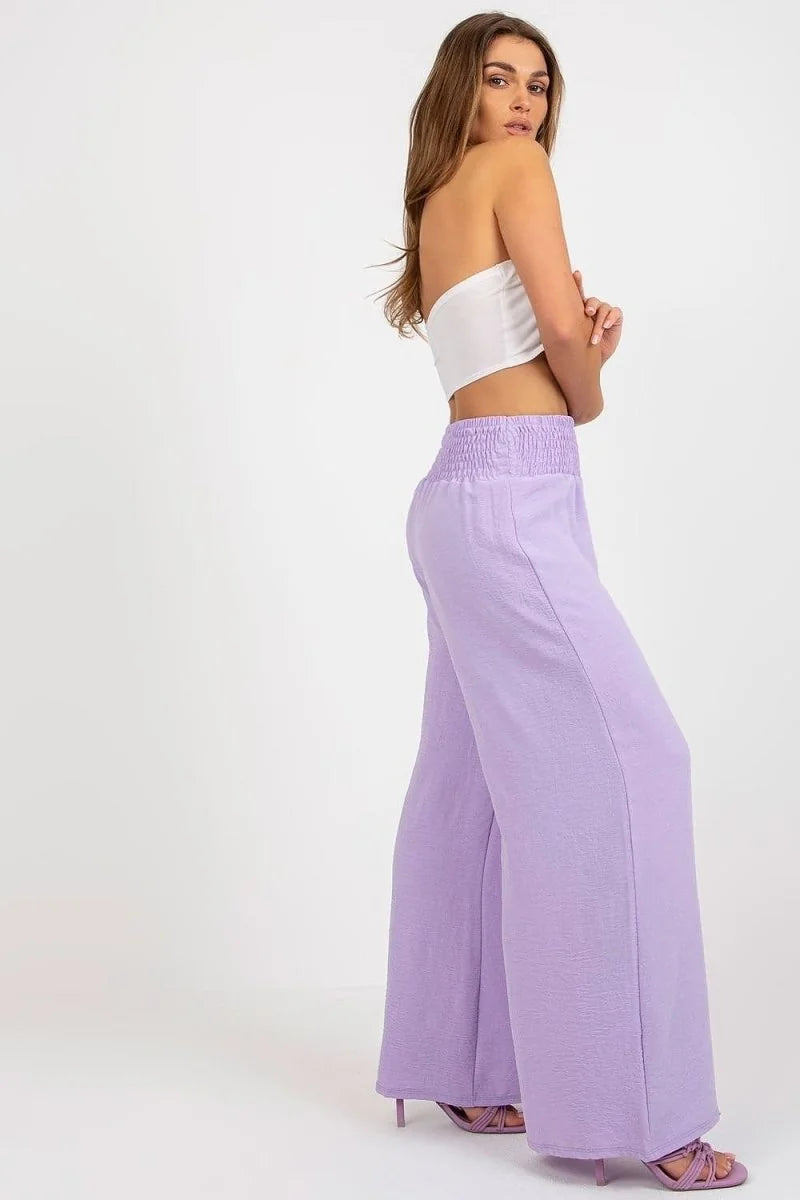 Violet wide-leg pants with textured fabric and a smocked waistband, shown on model.