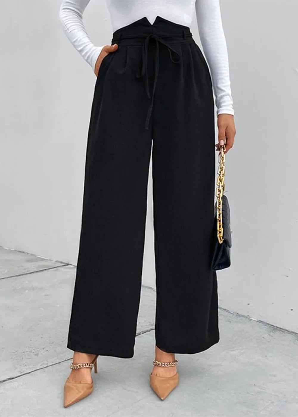 Black high-waisted wide-leg trousers with a drawstring tie, shown on a model with nude pointed-toe heels and a black handbag.
