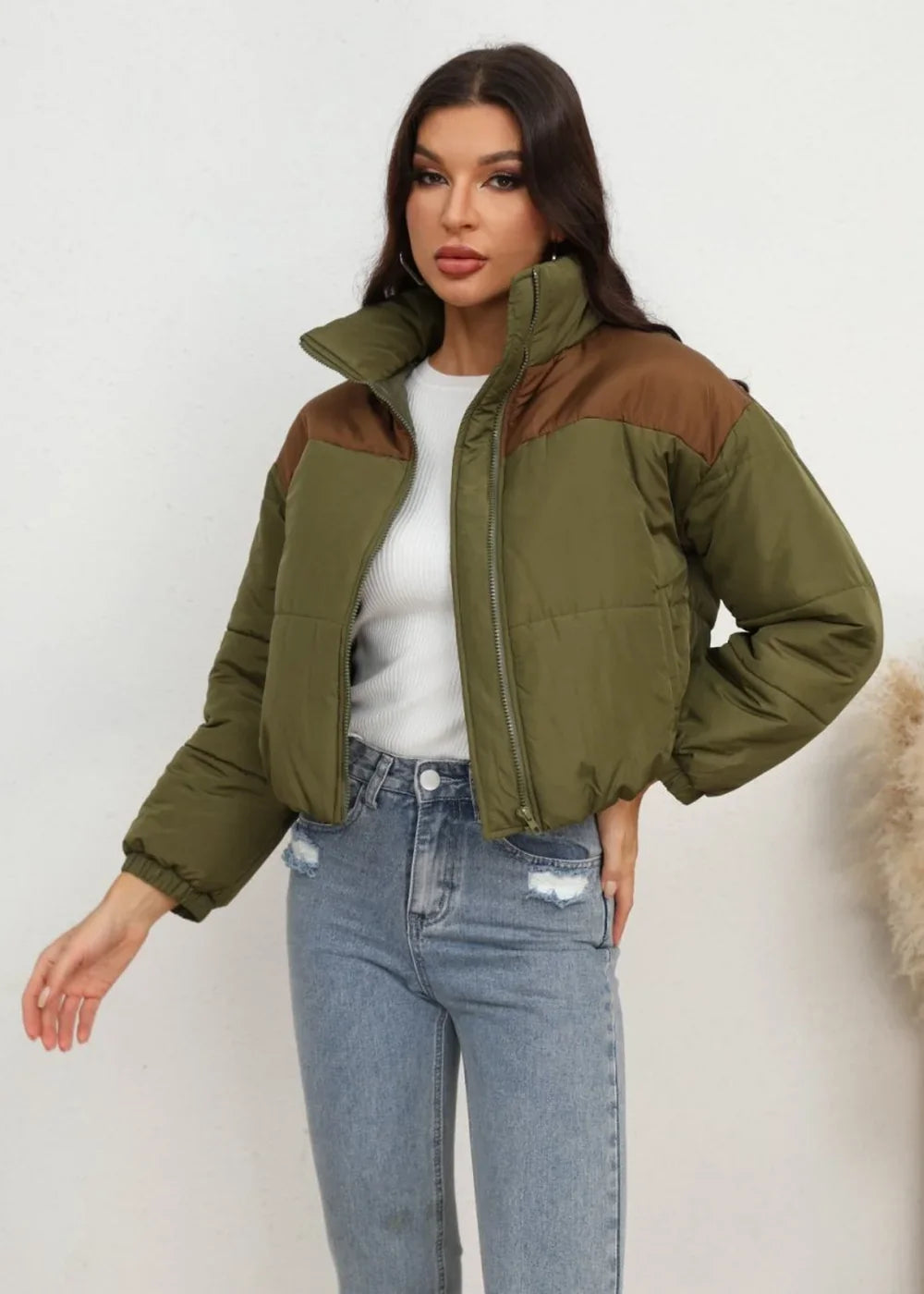Green and brown colorblocked puffer jacket with a high collar and zipper closure on a model.