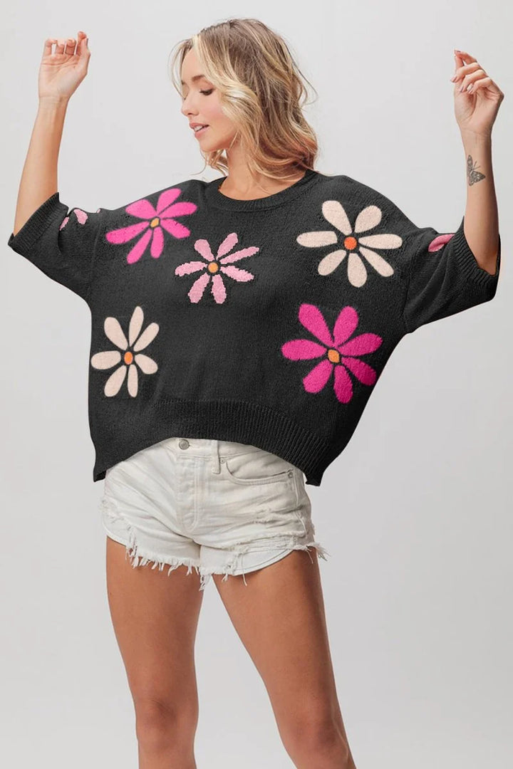 Black sweater with a colorful floral pattern, worn with distressed white denim shorts.