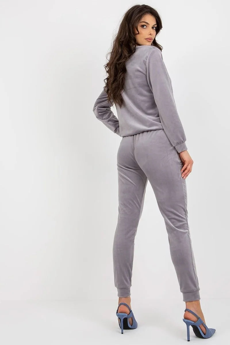 Woman from behind wearing a grey velvet tracksuit with blue high-heeled shoes.