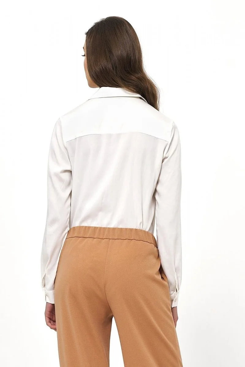 Back view of a woman wearing a white collared shirt and tan pants.