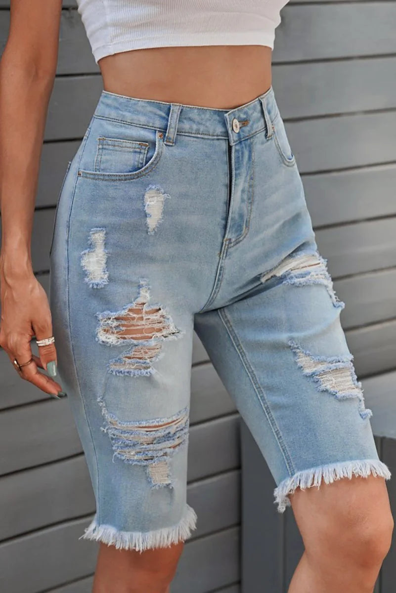 Light blue distressed denim shorts with frayed hem on model