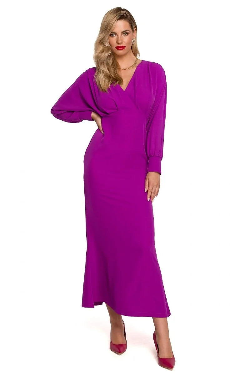 Full-length view of a woman in a vibrant purple, long-sleeved, V-neck wrap dress with a flared hem, paired with pointed-to...