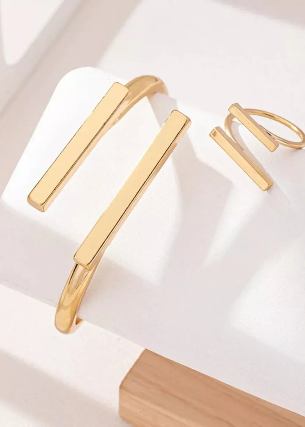 Gold-plated cuff bracelet and ring with minimalist bar designs.
