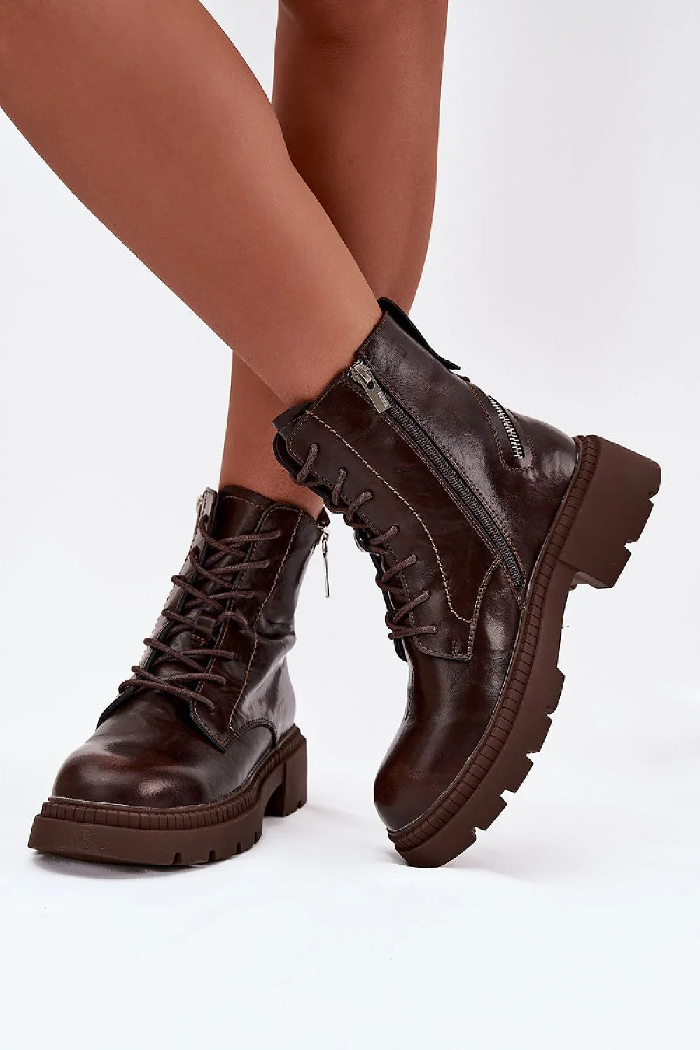 Brown leather lace-up combat boots with side zippers and thick lug soles on model.