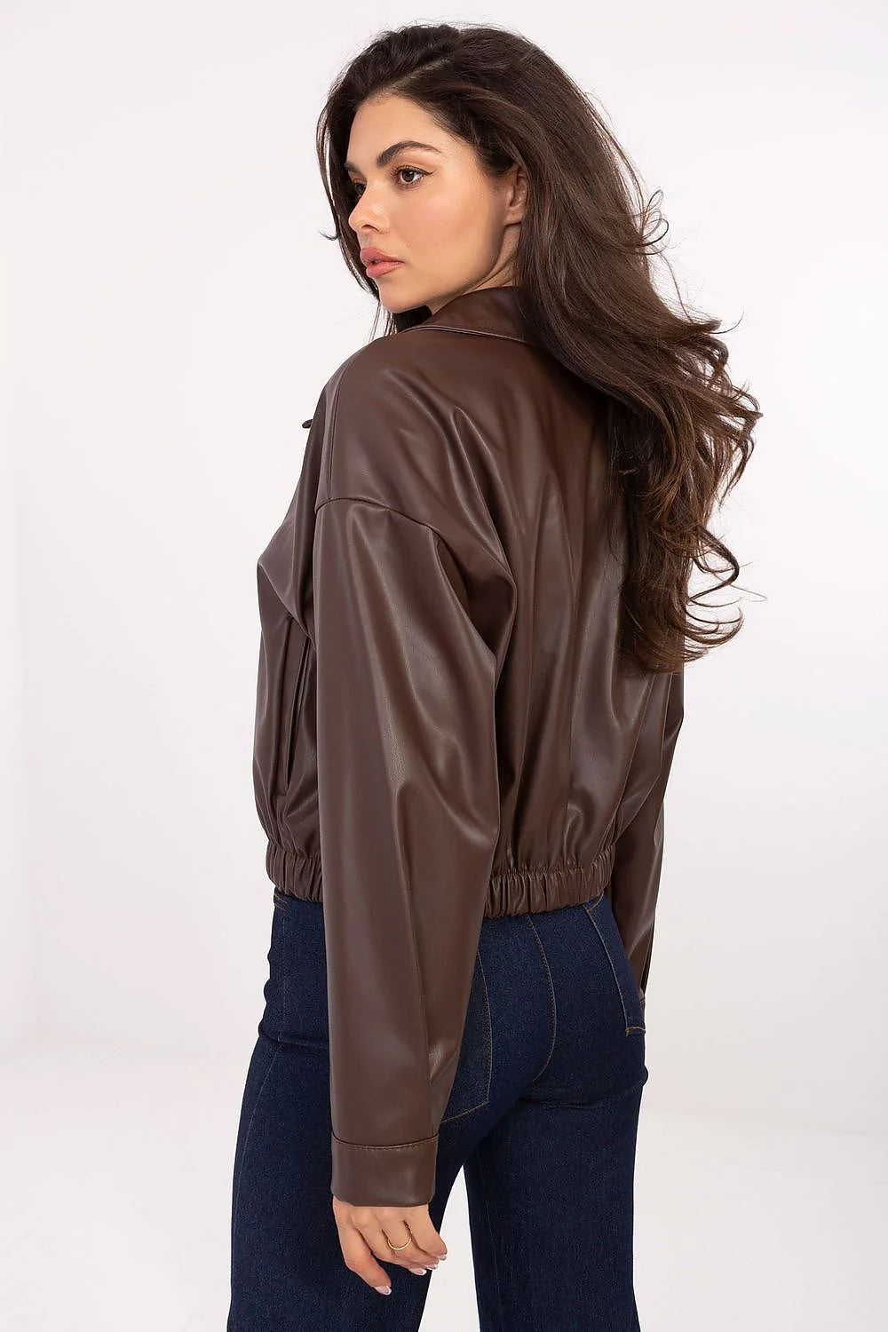 Woman wearing a brown faux leather bomber jacket and dark wash flared jeans.