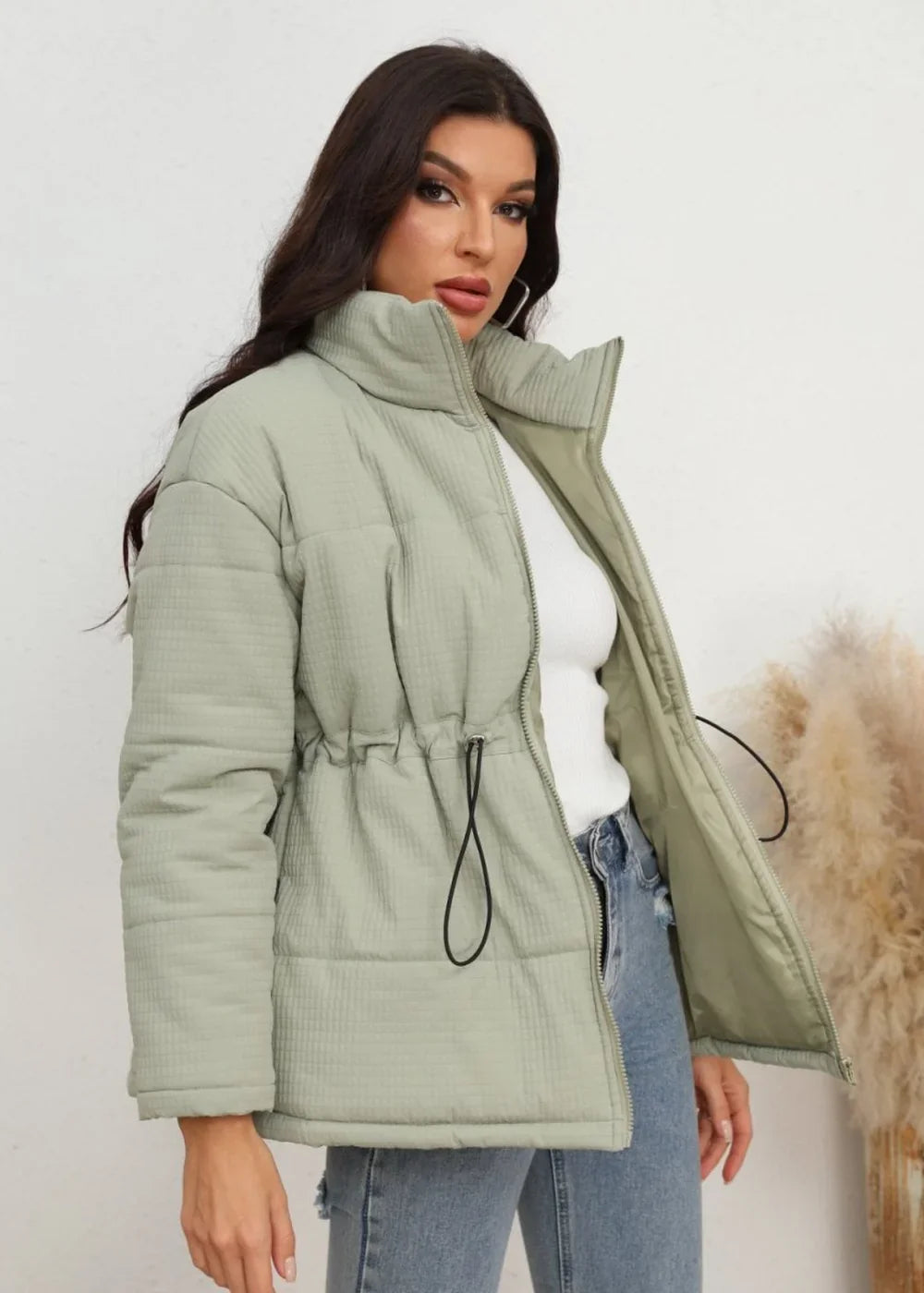 Light green quilted puffer jacket with drawstring waist on model.