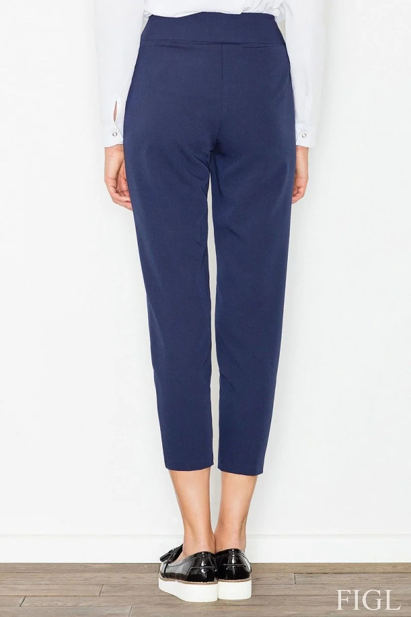 Back view of navy blue high-rise, 7/8 length polyester blend pants on model with black loafers.