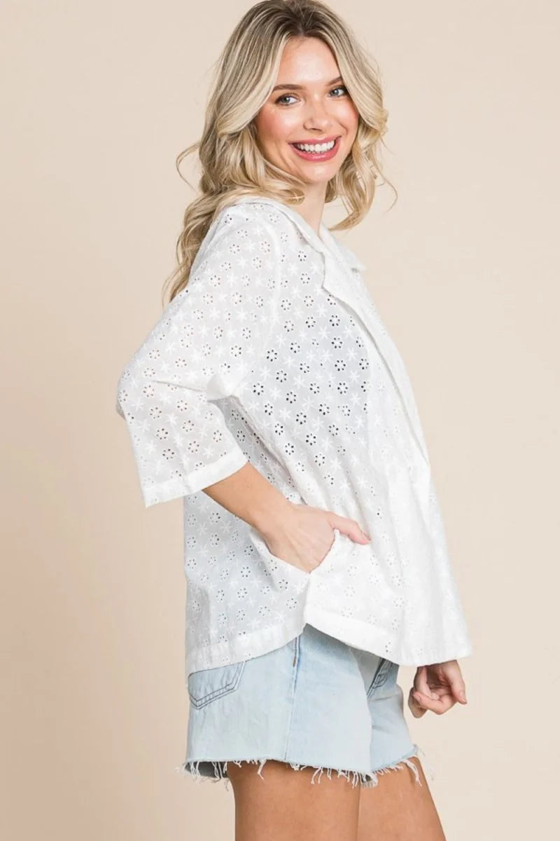 White eyelet jacket with 3/4 sleeves and pockets, worn over denim shorts on a model.