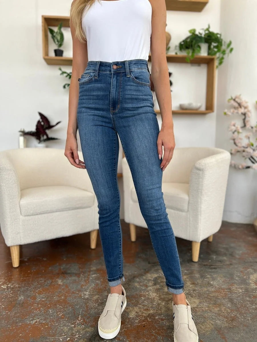 High-waisted, dark wash denim jeans with a regular fit, cuffed ankles, and a subtle whiskering effect.