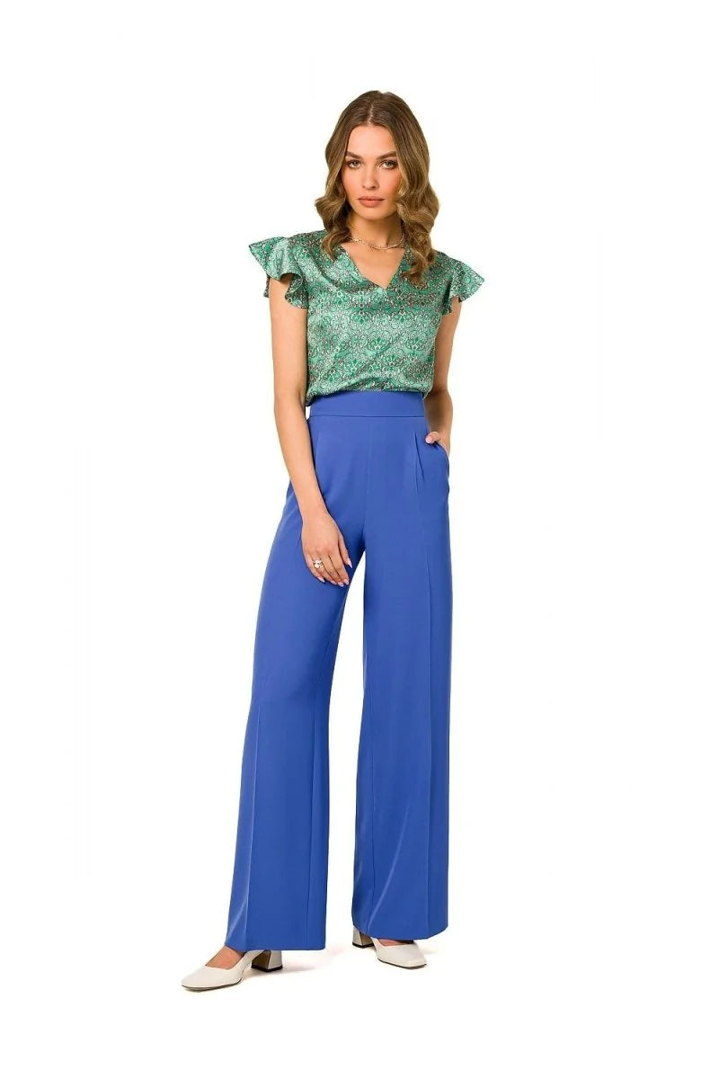 Model in high-waisted, royal blue, wide-leg pants with a v-neck green patterned top.