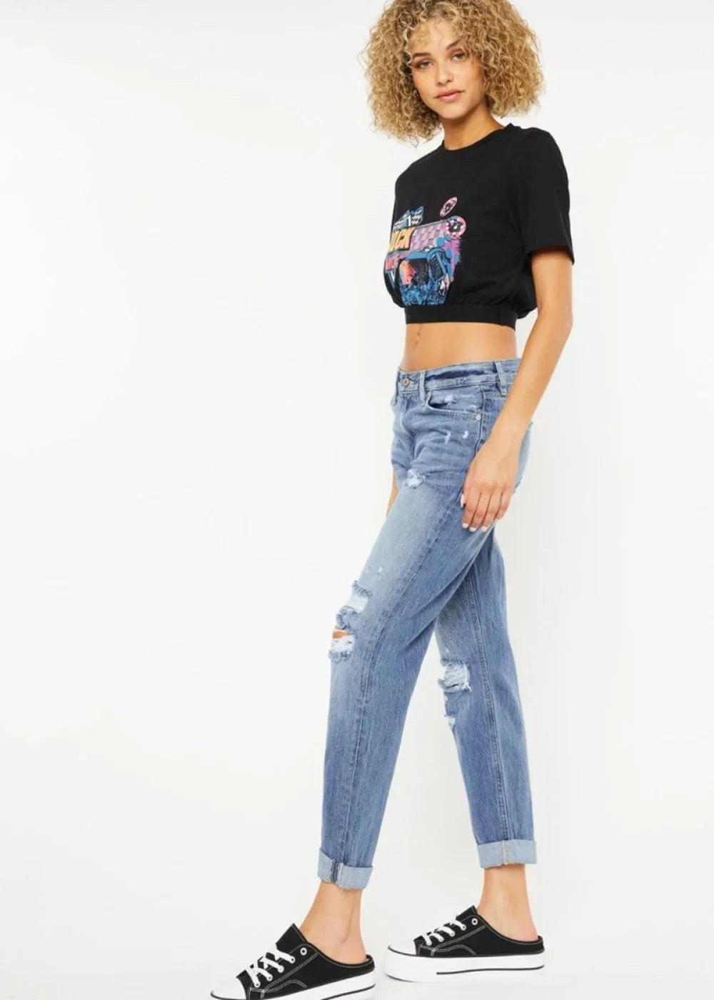 Distressed light wash denim jeans with rolled cuffs on a model.