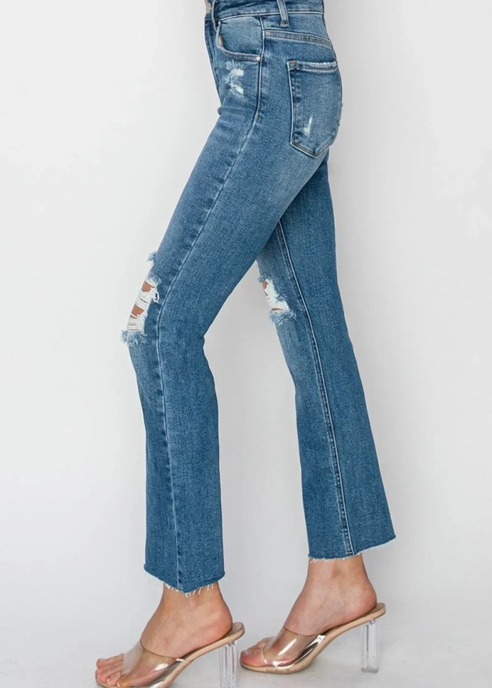 Model wearing medium wash high rise distressed ankle jeans