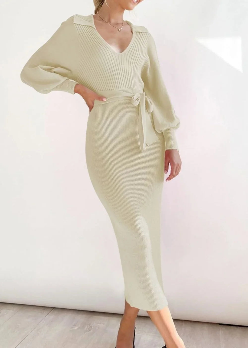 Cream ribbed knit midi dress with V-neck, tie waist, and balloon sleeves on a model.
