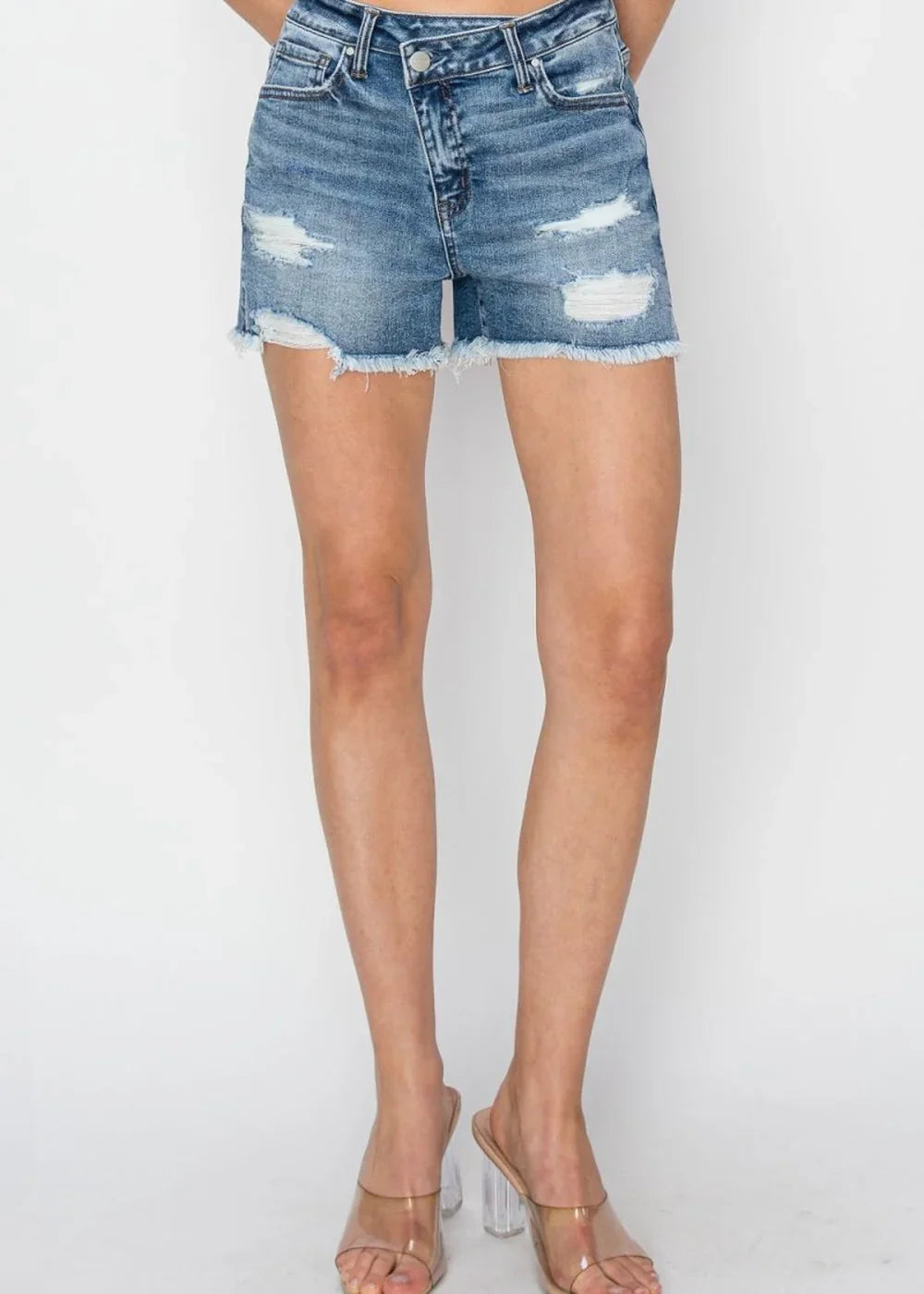 Distressed denim shorts with frayed hem and asymmetrical front closure, on model.