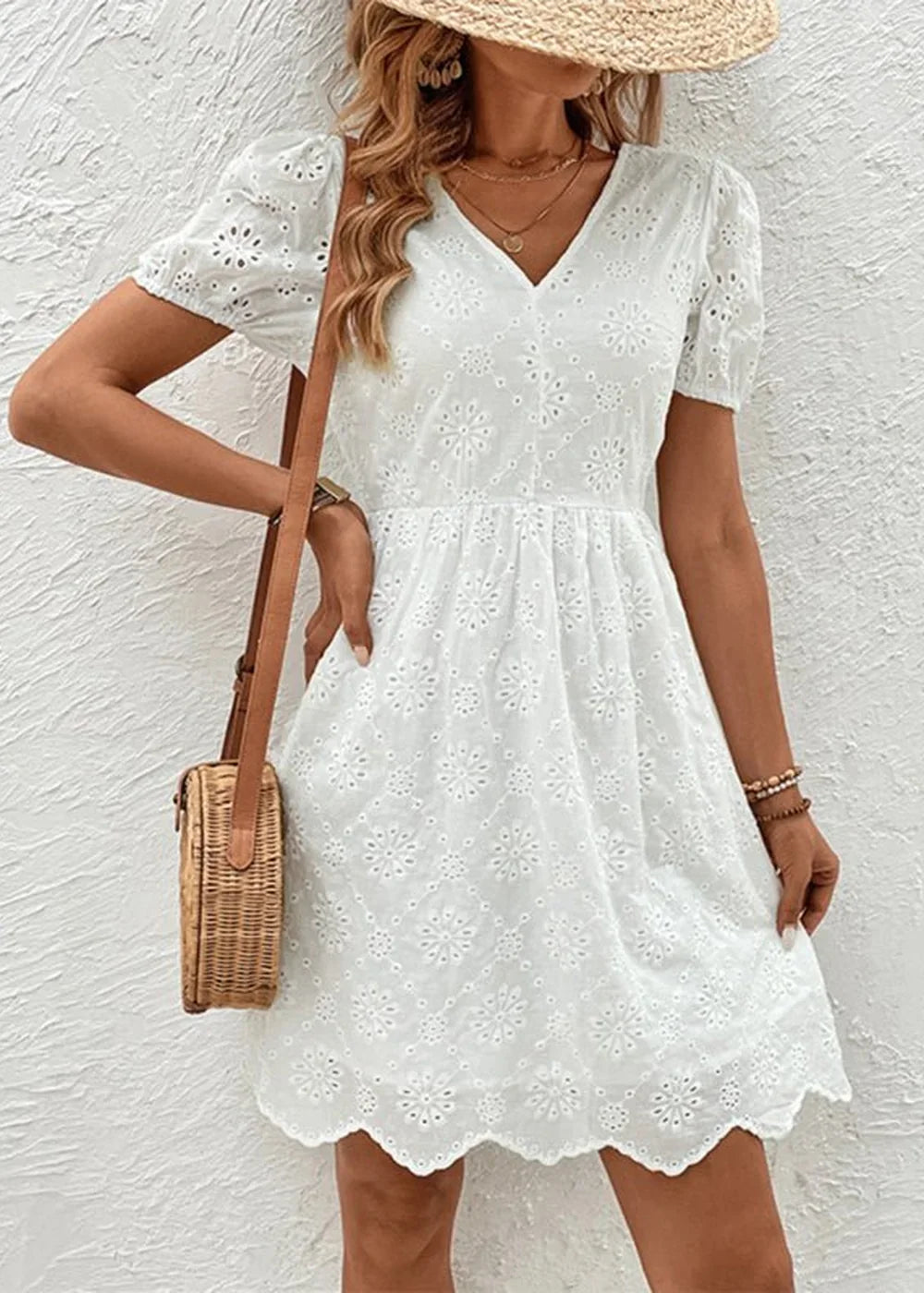 White eyelet mini dress with puff sleeves and a woven crossbody bag.