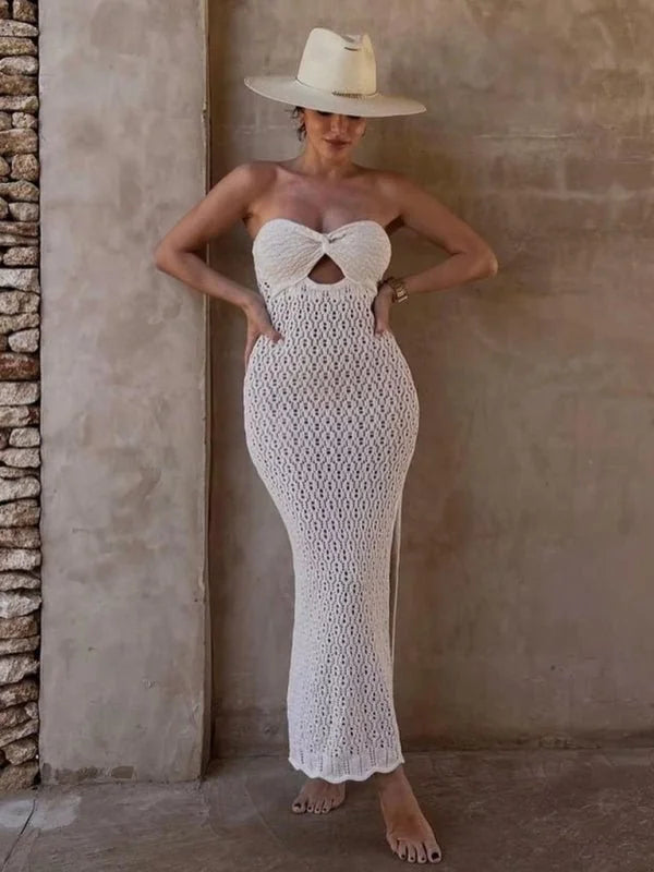 White crochet knit strapless maxi dress with a cutout bust detail and a wide-brimmed hat.