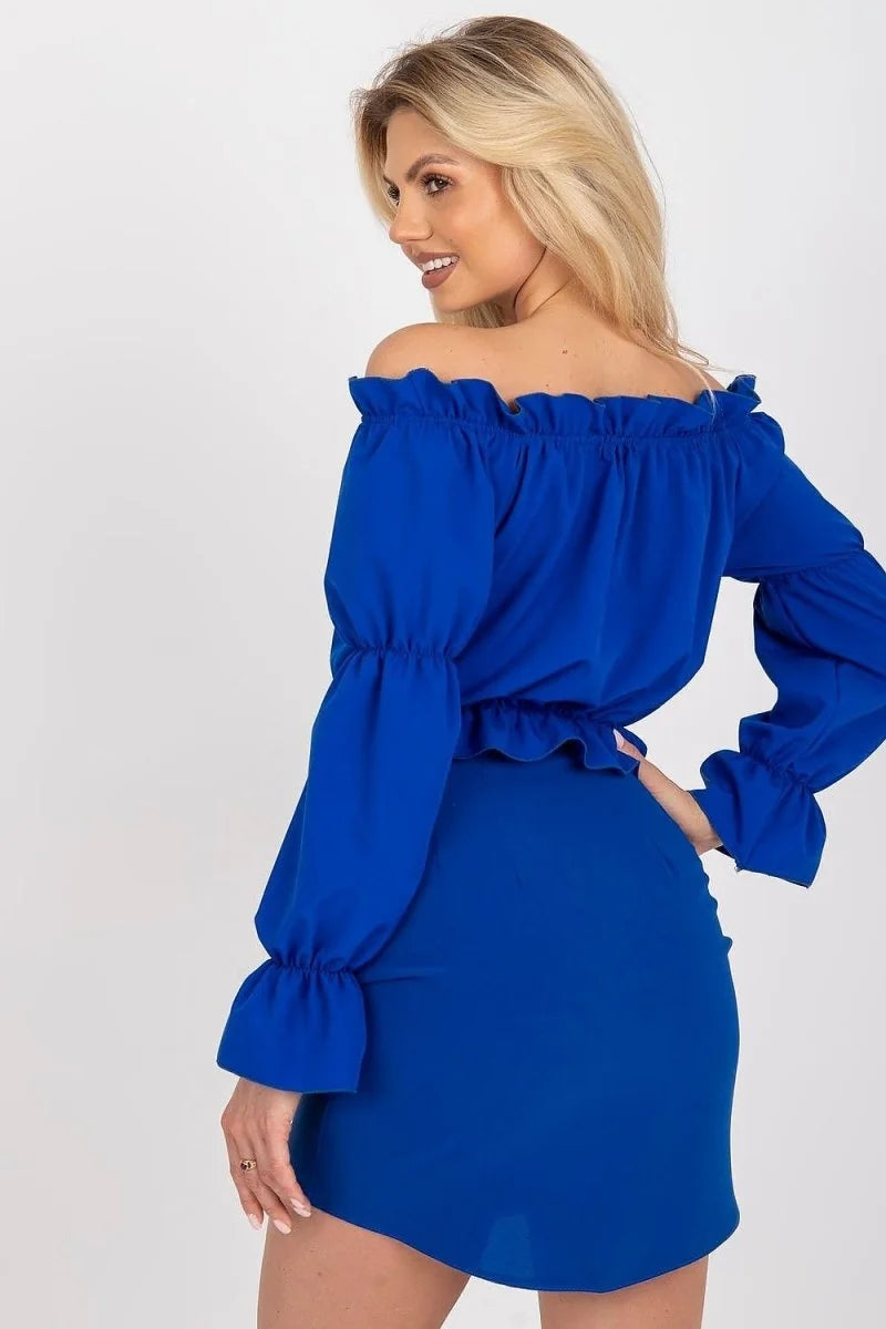 A woman in a royal blue off-the-shoulder top with ruffled neckline and cuffs, paired with a matching mini skirt.