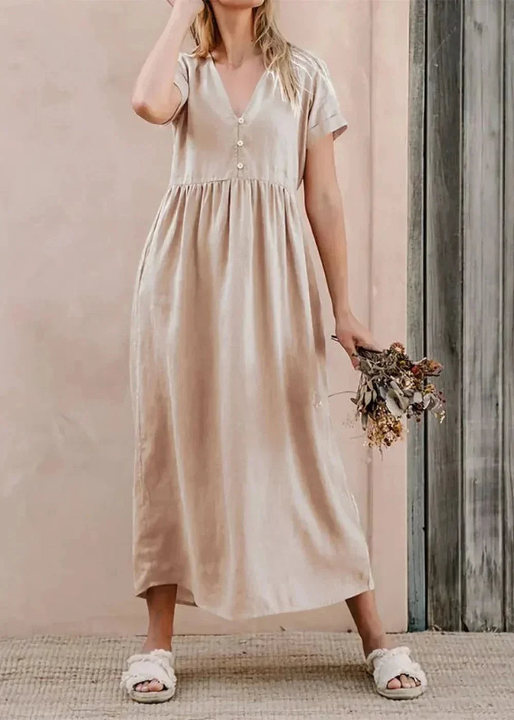 Beige cotton midi dress with V-neck and short sleeves, worn by a model holding dried flowers.