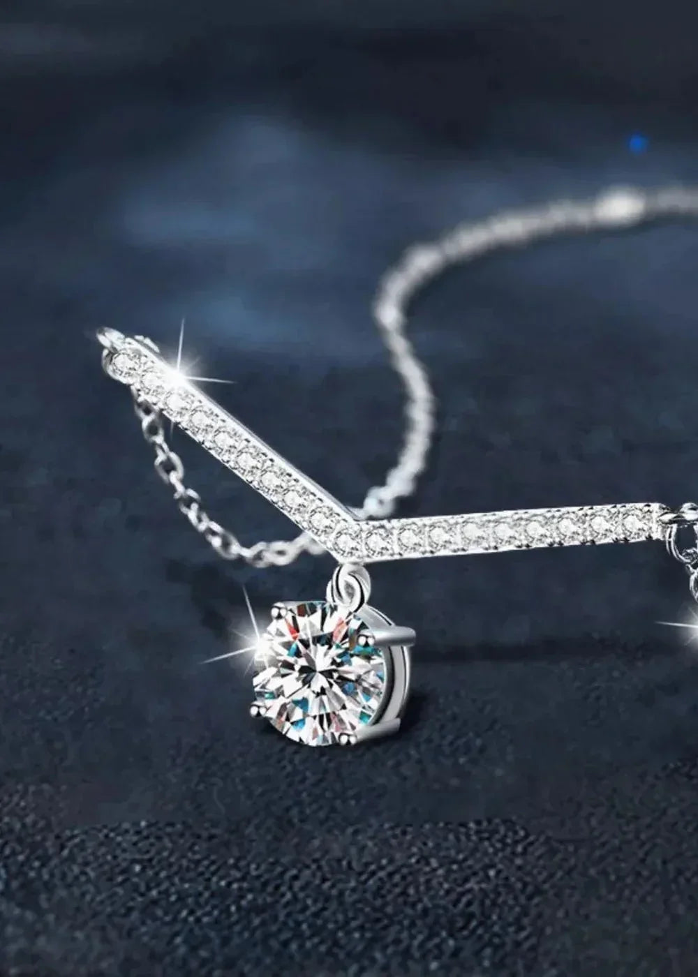 Close-up of a platinum-plated sterling silver necklace with a sparkling moissanite diamond pendant.