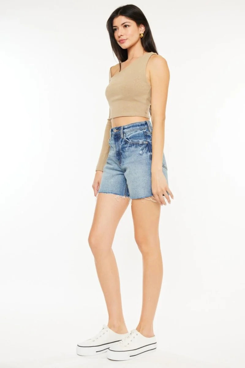 Distressed denim shorts with a frayed hem on a model.