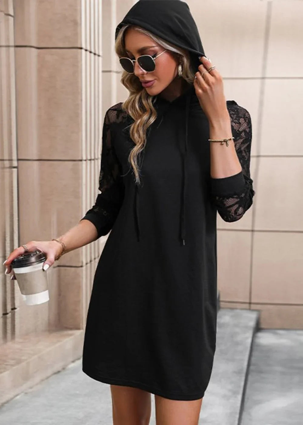 Black hooded sweater dress with lace sleeves, worn by a model holding a coffee cup.