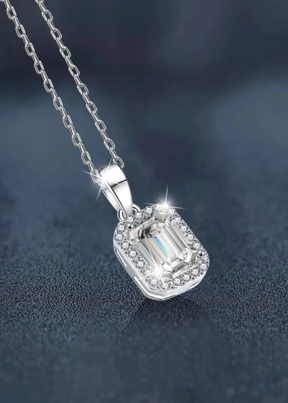 Close-up of a platinum-plated sterling silver necklace with a rectangular moissanite pendant surrounded by smaller stones.