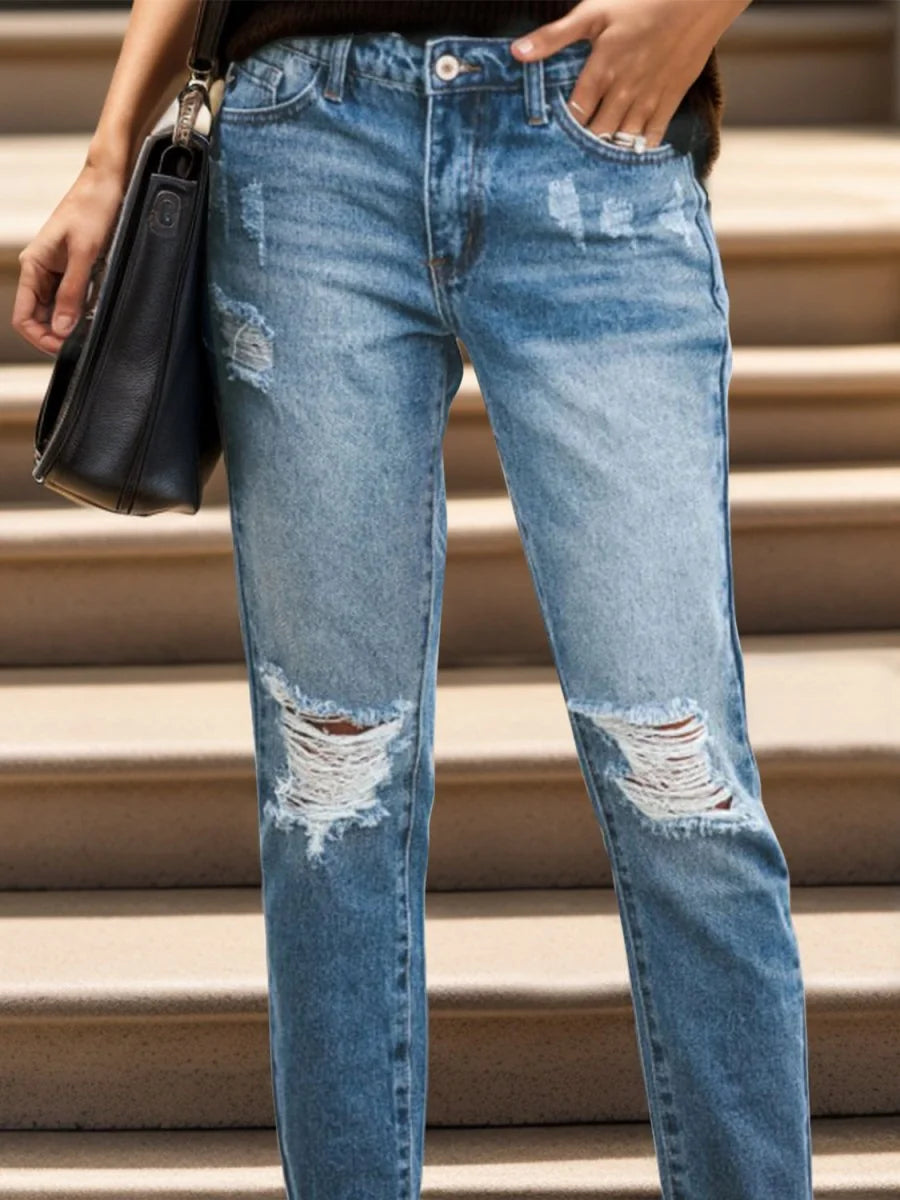 Distressed light blue denim jeans with ripped knees and a relaxed fit, shown on model.