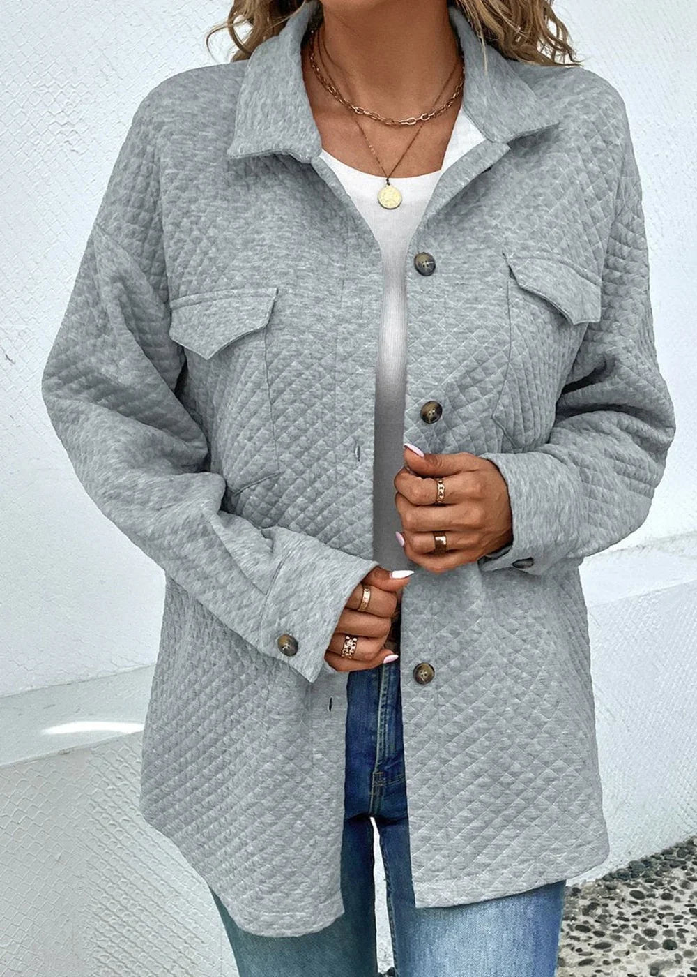 Quilted grey button-up jacket with two chest pockets, worn by a model with gold jewelry.
