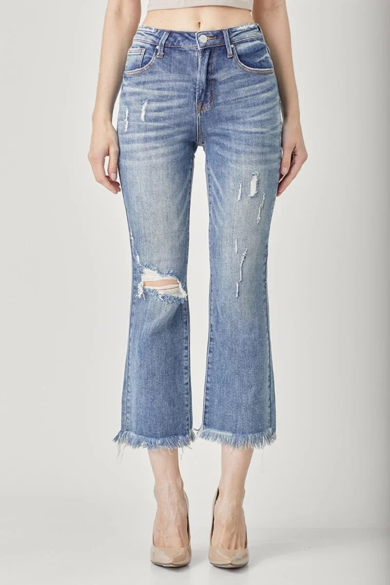 Distressed medium wash denim cropped flare jeans with frayed hem and raw edges.