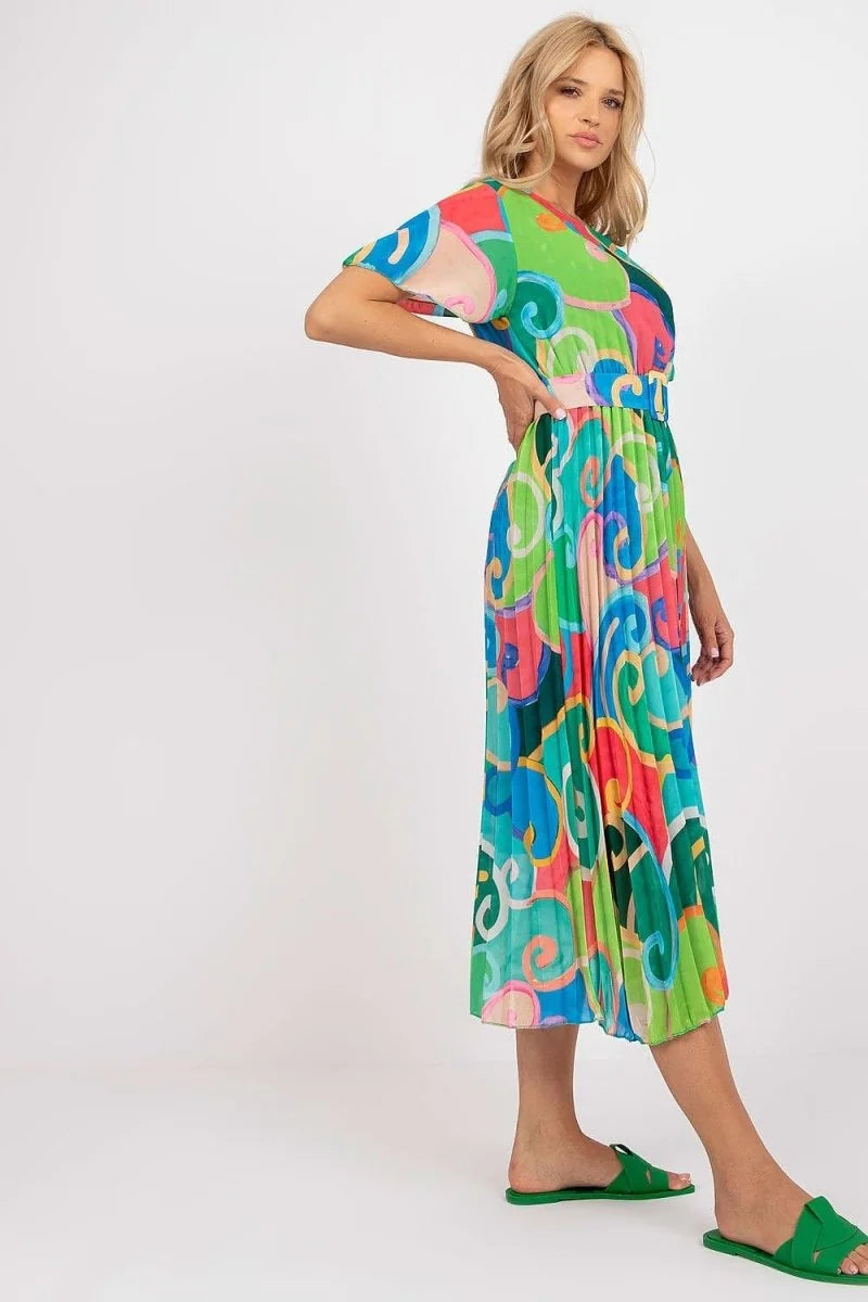 Vibrant green and blue swirl print pleated midi dress with short sleeves and green slide sandals.