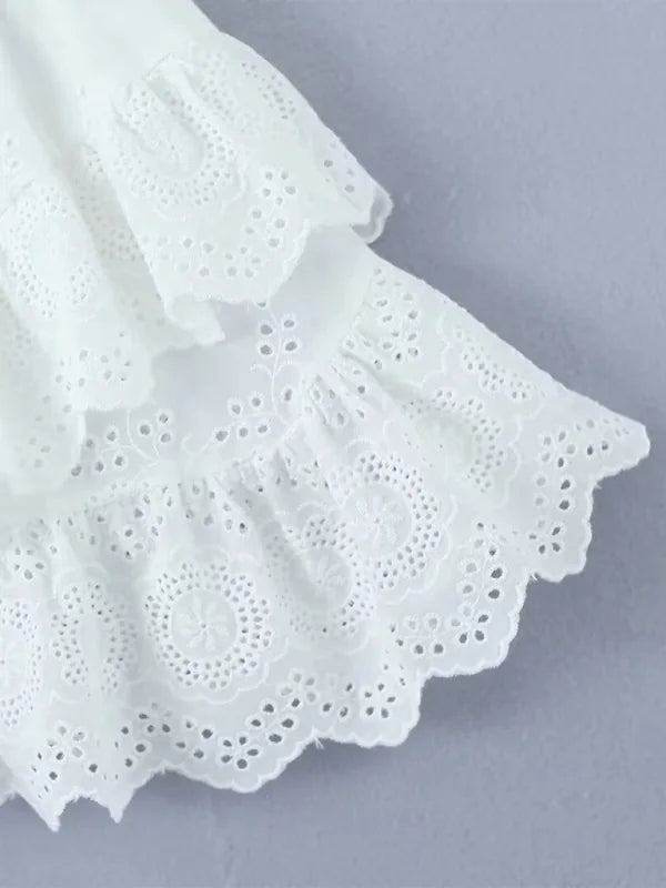 Close-up of white eyelet fabric with tiered ruffles and a scalloped hem.