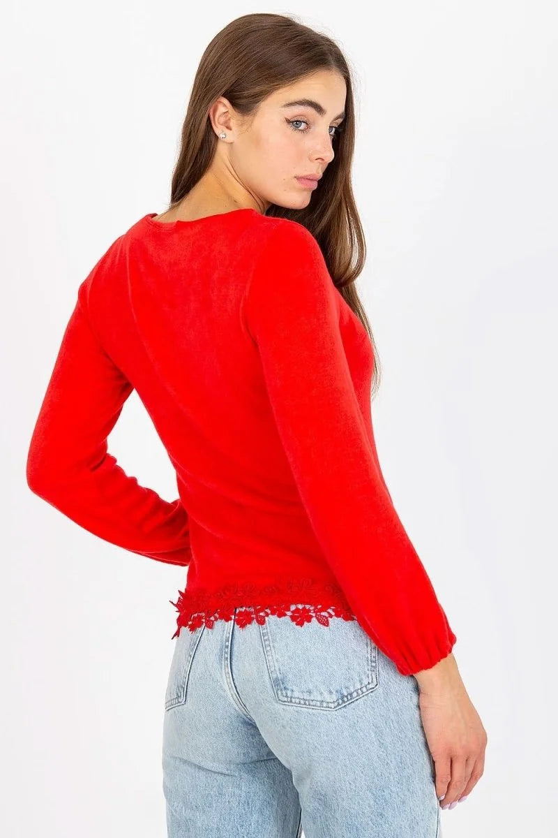 Red wool sweater with lace trim on the hem, worn with light wash denim jeans.
