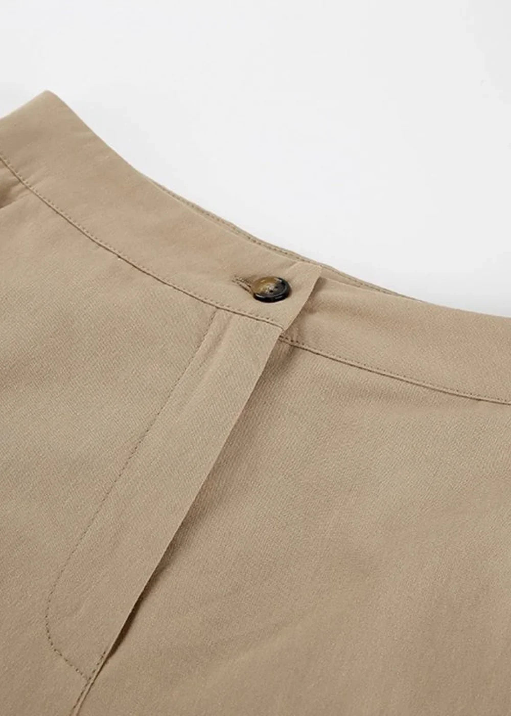 Close-up of tan trousers with a button closure and textured fabric.