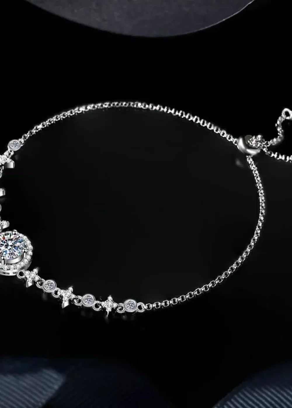 Silver chain bracelet with a large faceted gemstone and small diamond-like accents.